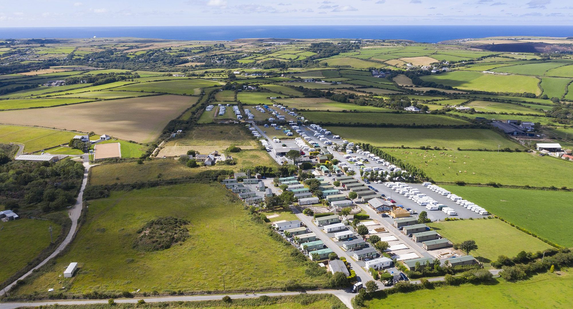 aerial view of campsite with grass and hardstanding pitches for tents, caravans and motorhomes